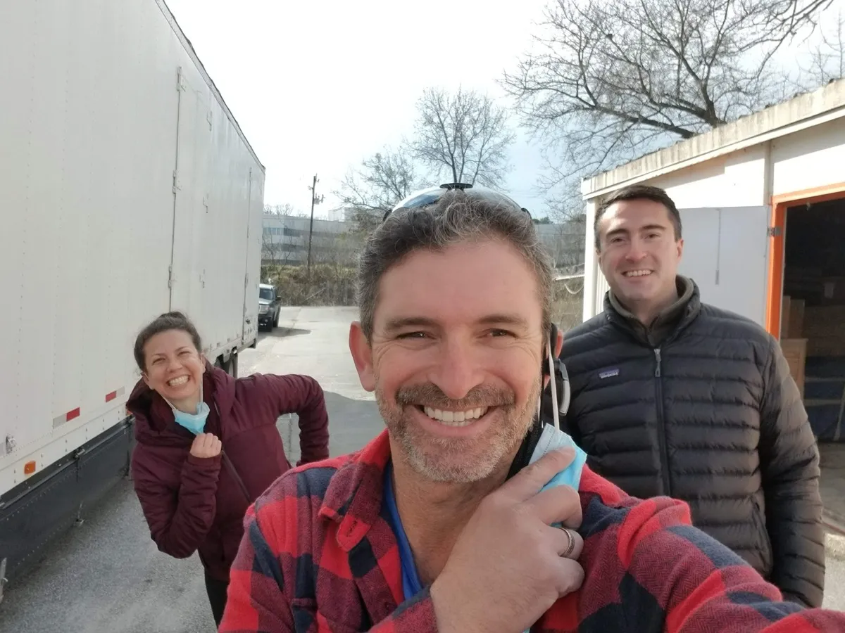 A happy customer laughing with the Moving Pro Inc crew beside the moving truck